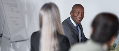 Business professionals in a meeting with a focus on a person presenting in front of a flip chart.
