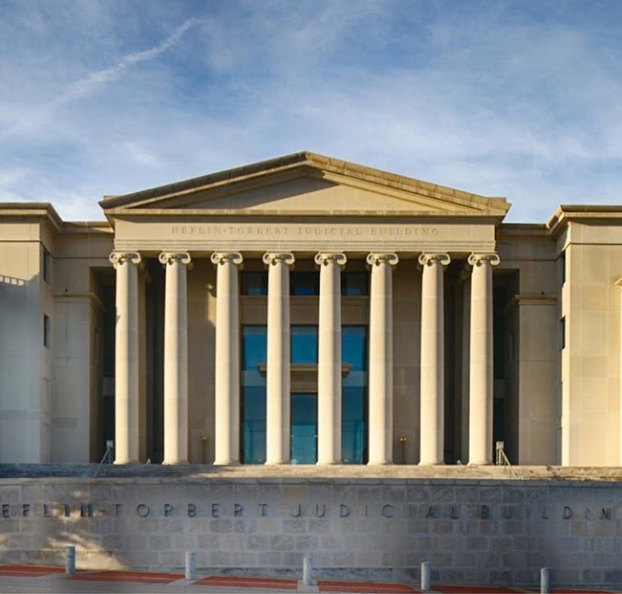 Vue frontale de l’édifice judiciaire Heflin-Tortert comportant une façade classique avec des colonnes sous un ciel dégagé.