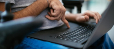 Close-up of a man's hands using a laptop, one hand on the trackpad and the other gesturing