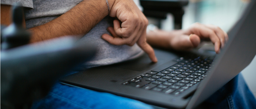 Close-up of a man's hands using a laptop, one hand on the trackpad and the other gesturing