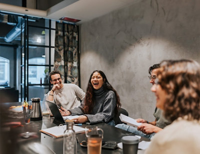 A group of people sitting around a table laughing.