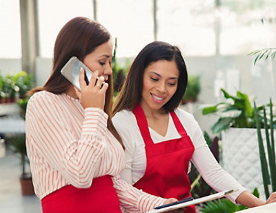 A woman in a red apron talking on a cell phone.