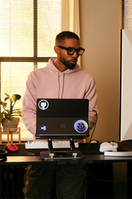 Person standing at desk working on laptop in a home office setup