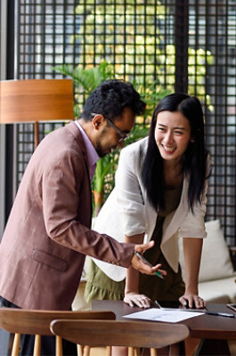Two colleagues discussing work over a table in a contemporary office space