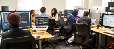 Team working together in an open office with multiple desks and monitors