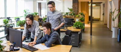 Team reviewing work together at a desk in a plant‑filled office