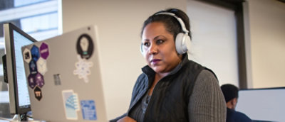 A woman wearing headset looking at the laptop.