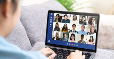 Persona che partecipa a una videoconferenza da un portatile, con più partecipanti visibili sullo schermo.