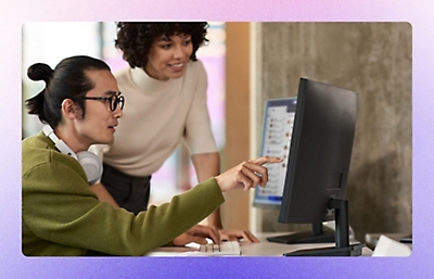  Two employees discussing something while also working on computer.