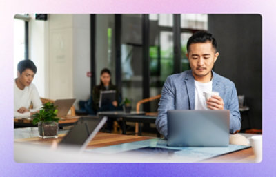 A man working on laptop with colleagues sitting behing him working.