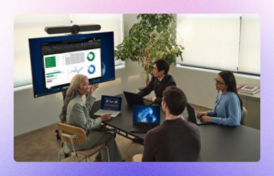 A group of employees in conference room looking at presentation on screen and discussing.