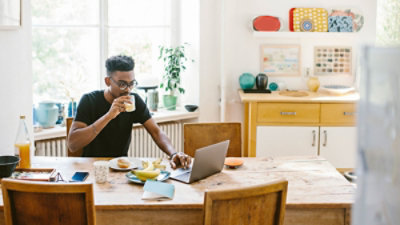 A person sitting at a table with a computer and a glass of juice