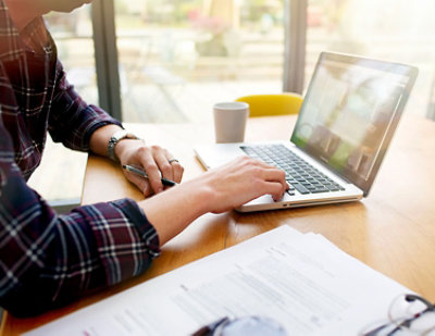 A person's hands typing on a laptop keyboard.