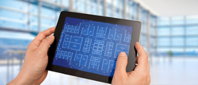 Una persona ha in mano un tablet su cui sono visualizzati progetti architettonici digitali 