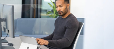 A man sitting in a chair using a laptop.
