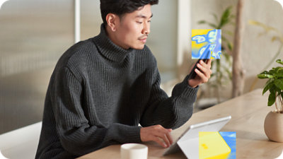 A man using a cell phone while sitting at a table.