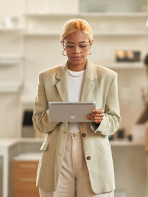 A person holding a tablet while wearing a beige suit.