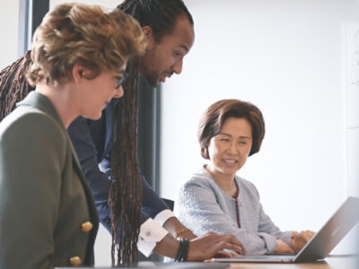 A man and woman smiling at a laptop.