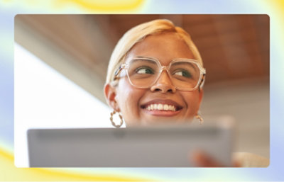 En kvinde, der holder en tablet og smiler.