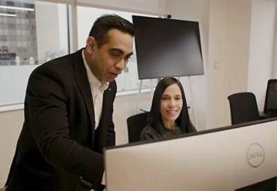 A men and women looking at a desktop.