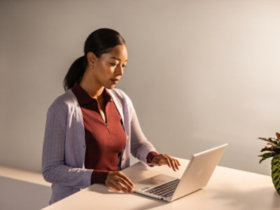 A women sitting at a desk and working on a laptop.