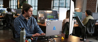 A man sitting at a desk and working on laptop.