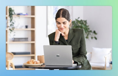 一位身穿西装的女士坐在桌旁，桌前放着一台笔记本电脑。