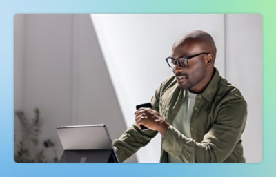 一位男士拿着手机，看着笔记本电脑。