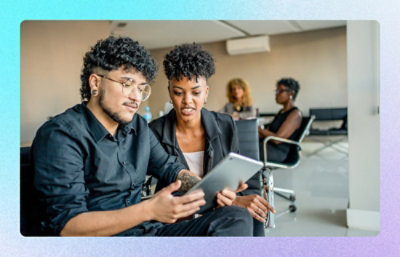 Two colleagues reviewing content on a tablet in a conference room