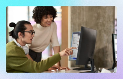 Colleagues collaborating at a desktop computer, one pointing at the screen