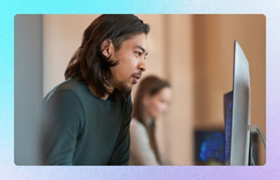 Person leaning toward desktop monitor in modern office workspace