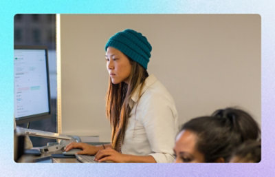 Person standing at workstation using desktop computer in office environment.