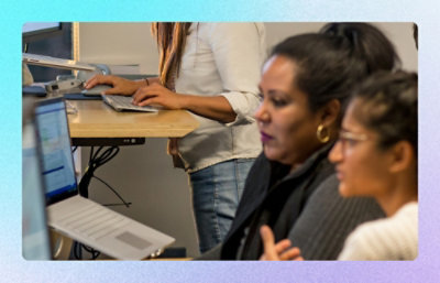 Team collaborating at a shared desk with laptop and desktop computers