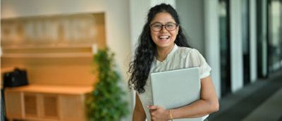A woman smiling while holding a laptop
