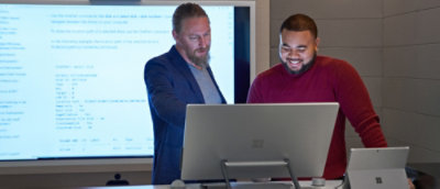 Two persons looking on computer screen.
