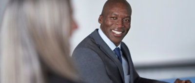 A close-up of a person wearing a suit and tie smiling at the camera.