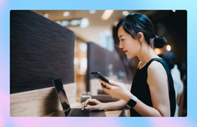 Una mujer usando un portátil y un teléfono.