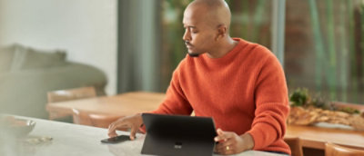 Un hombre con un manto naranja usando un portátil en una mesa.