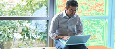 Un hombre sentado en una silla con un portátil.
