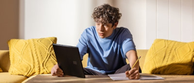 A man holding a tab in his hand and writing.