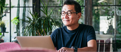 A man in glasses looking at a laptop.