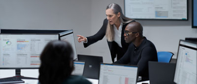 אדם מצביע על מסך מחשב כשברקע נראים מחשב נישא וראש מטושטשים.