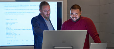 גבר בחליפה עומד מול מחשב נישא.