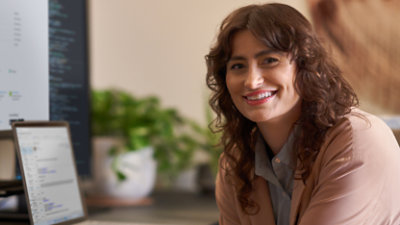 אישה יושבת ליד שולחן עבודה ומחייכת