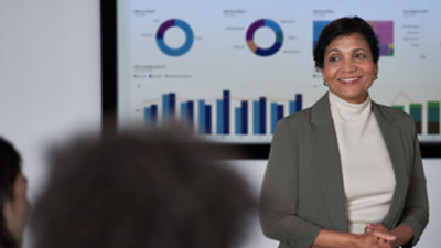 אדם עומד מול מסך גדול כשהוא לובש חליפה.