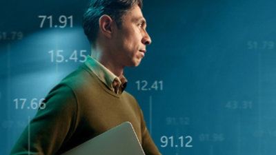 A man holding a laptop in front of a blue background with white numbers.