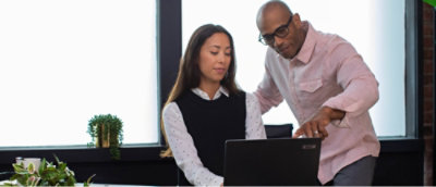 一名男士和一位女士在辦公室的辦公桌前一起工作。