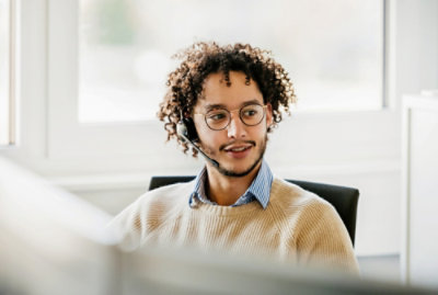 A man with curly hair wearing a headset.