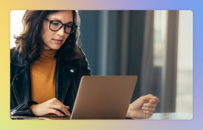 A women wearing a specs working on a laptop.