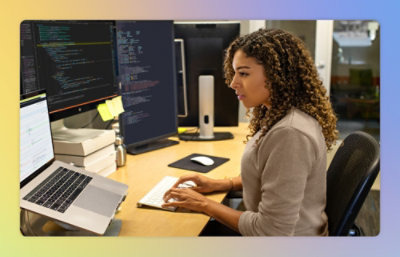A women sitting at a desk and working on a laptop.